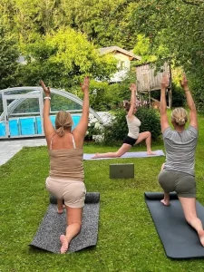 Drei Frauen bei Yogaübungen auf Matten im Garten