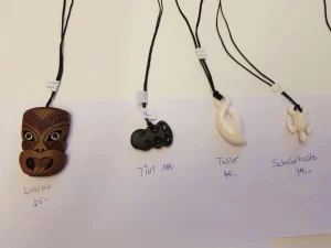 Maori-Anhänger aus Holz, Jade und Knochen an Bändern mit Preisschildern