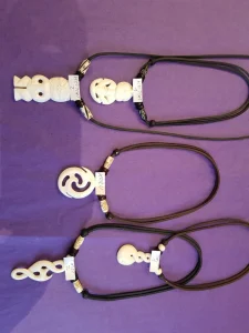 Maori-Schmuck aus Knochen an schwarzen Bändern auf violettem Tuch