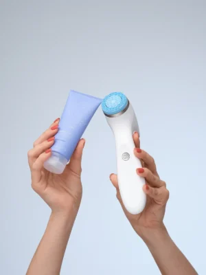 Hände halten das LumiSpa-Gerät und eine Tube Activating Cleanser
